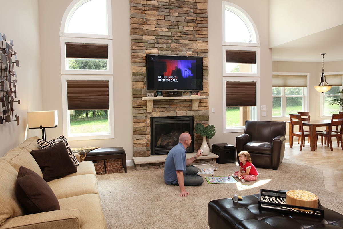 Man and child playing a board game while closing room darkening honeycomb shades with remote control