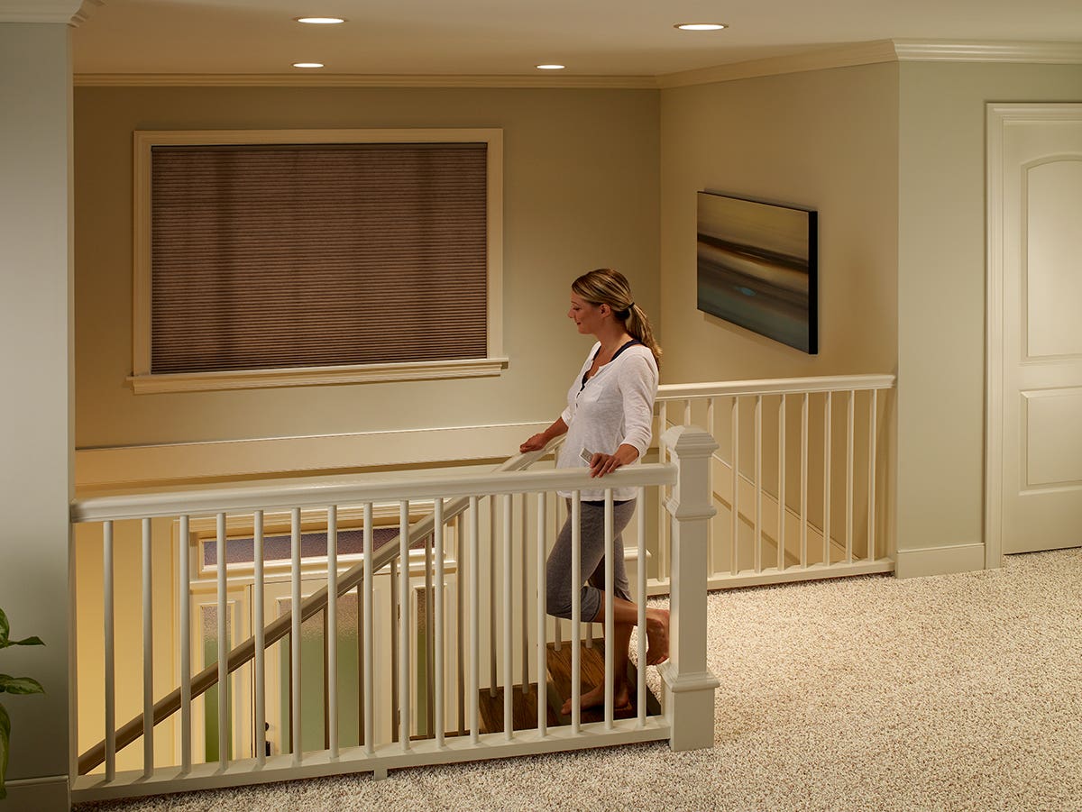 Woman walking down the steps of a two story foyer with closed single-cell inside mount honeycomb shades