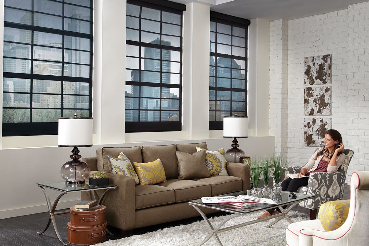 Woman sitting in loft living room with closed sheer roller shades in charcoal