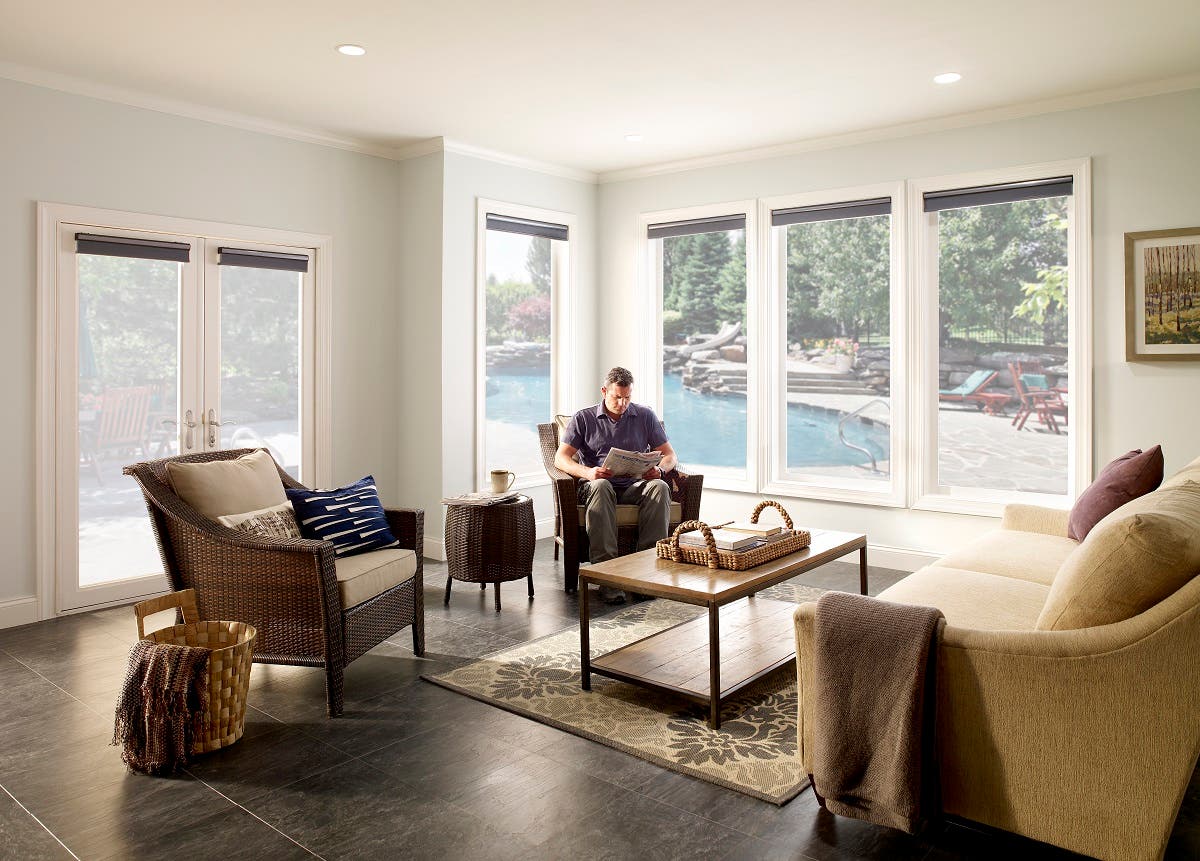 Man reading the paper in sunroom with open honeycomb shades in color storm