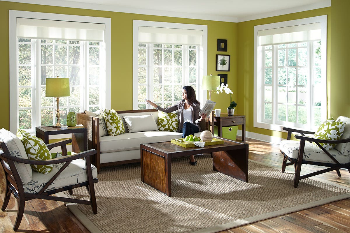 Woman in Bright Sunroom Using Remote-Controlled White Roller Shades