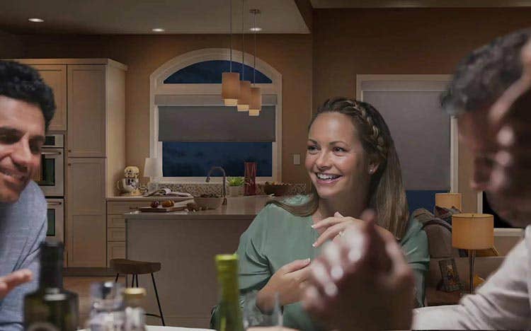 Group of friends sitting in kitchen laughing with gray roller shades halfway open