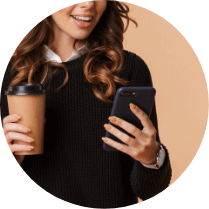 Woman smiling with phone in one hand, and coffee in the other hand