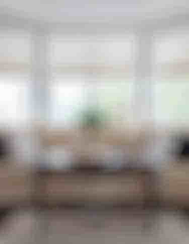 Living room with white honey comb blinds partially open, tan couch and wooden coffee table centered