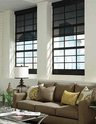 Room with smart blackout shades, couch that has accent pillows, coffee table, and side table