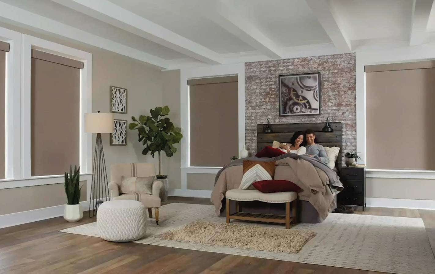 Couple in bed enjoying motorized window blinds that are blocking the light out