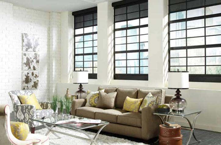 View of modern living room with motorized blackout shades in the windows behind the couch